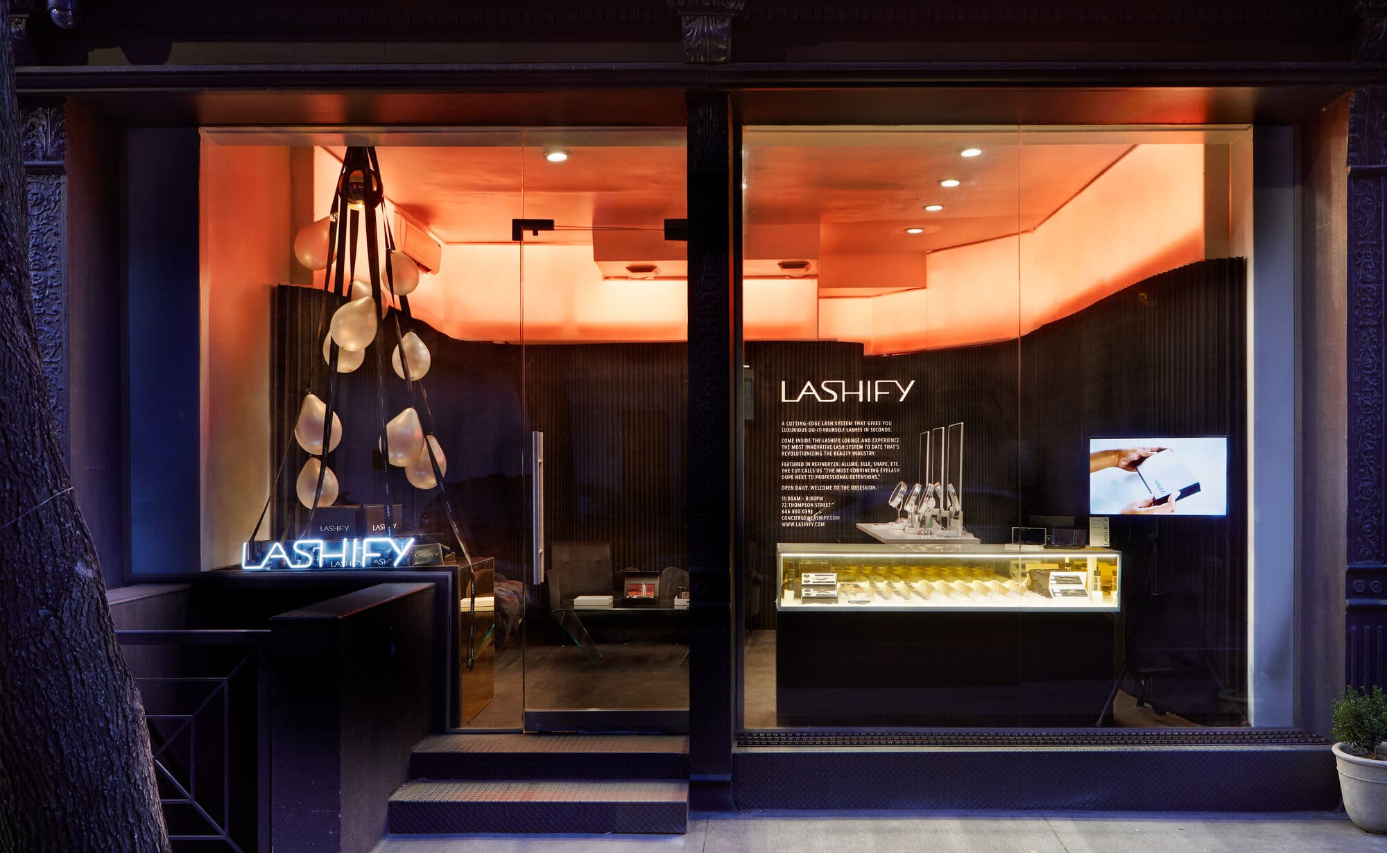 Finished store at night, orange light spilling onto the sidewalk