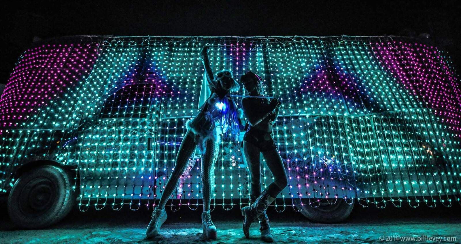 Dancers silhouetted against the LED skin, teal and purple