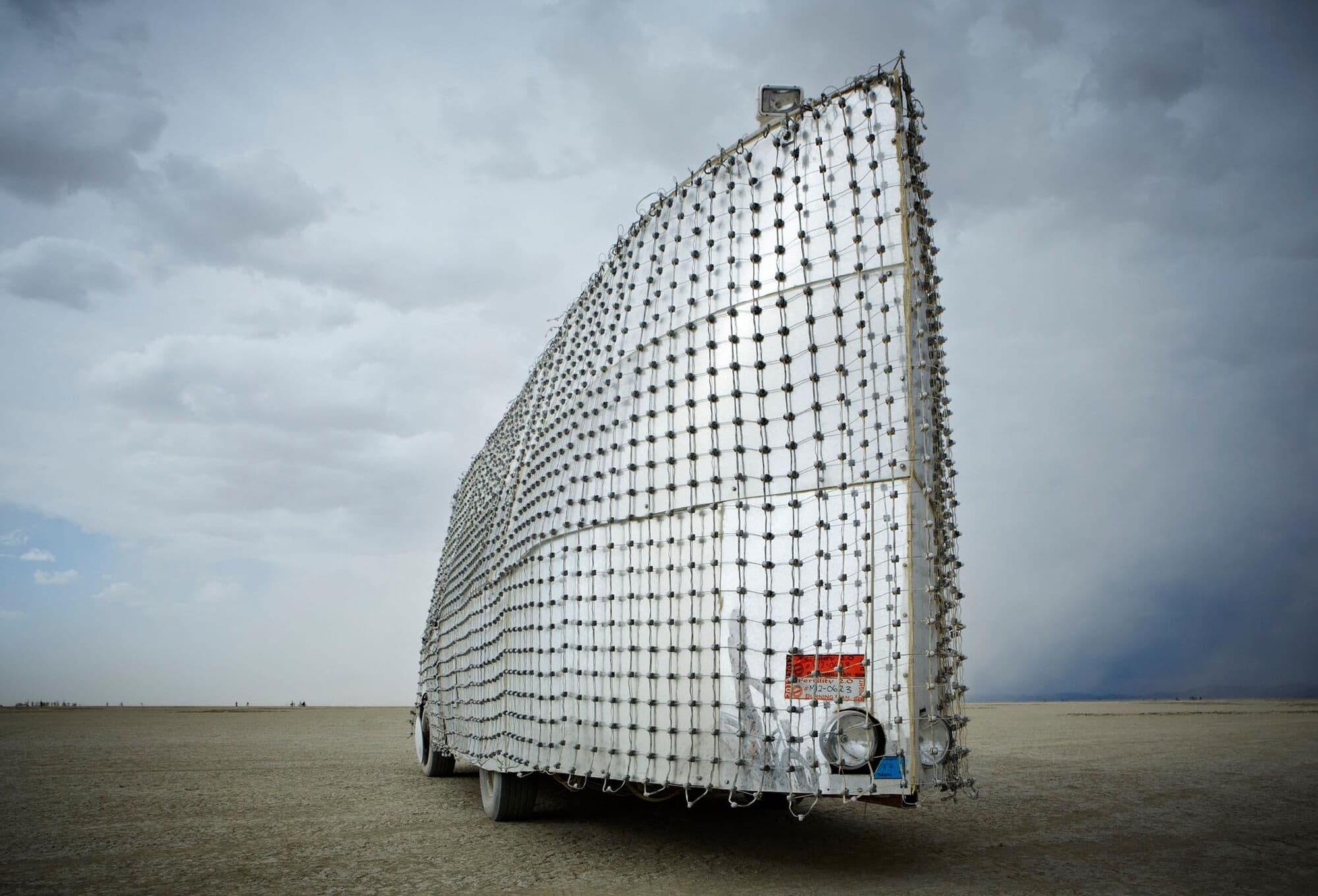 Rear three-quarter view — the mesh structure visible against dramatic sky