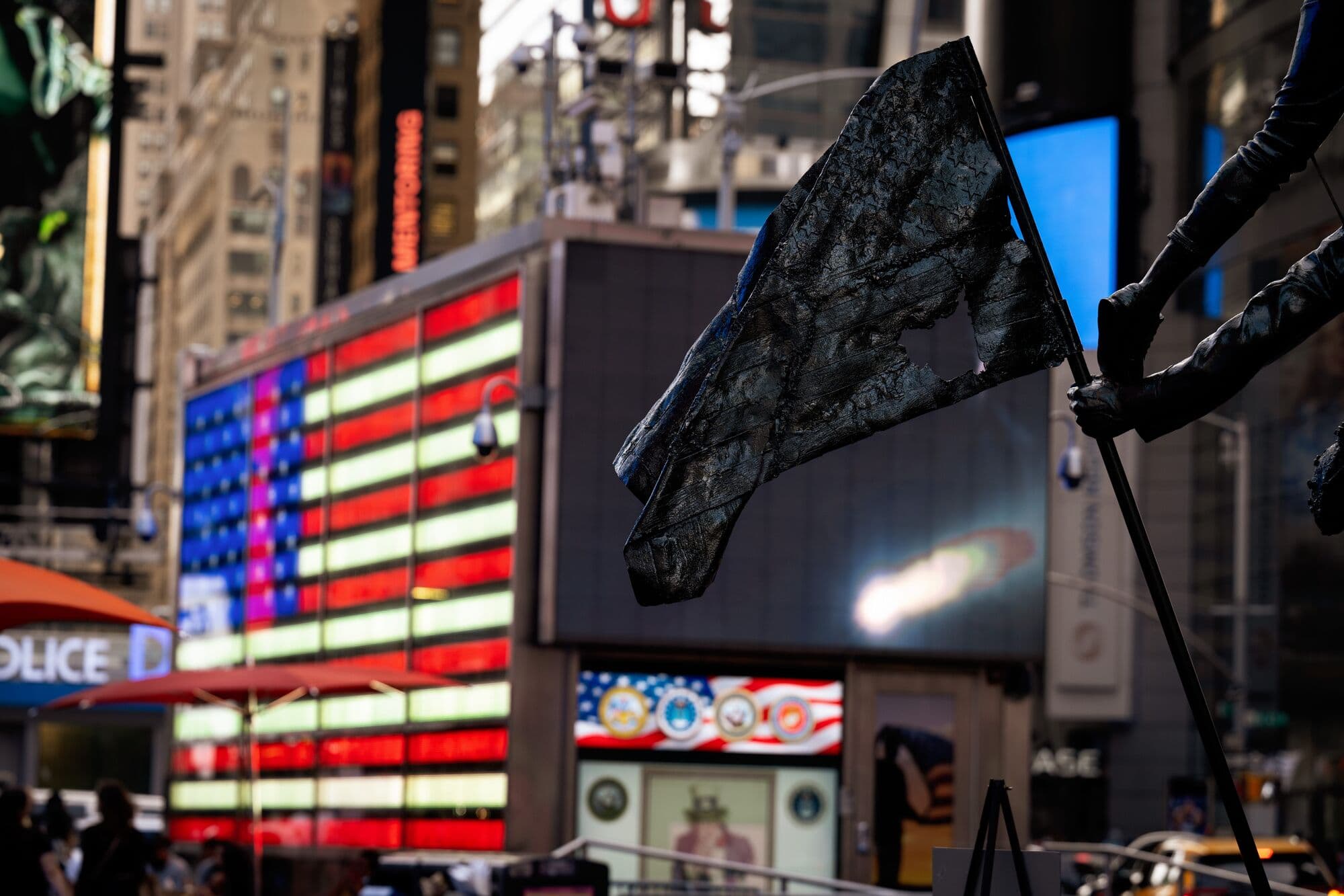 Tattered flag against LED American flag in Times Square