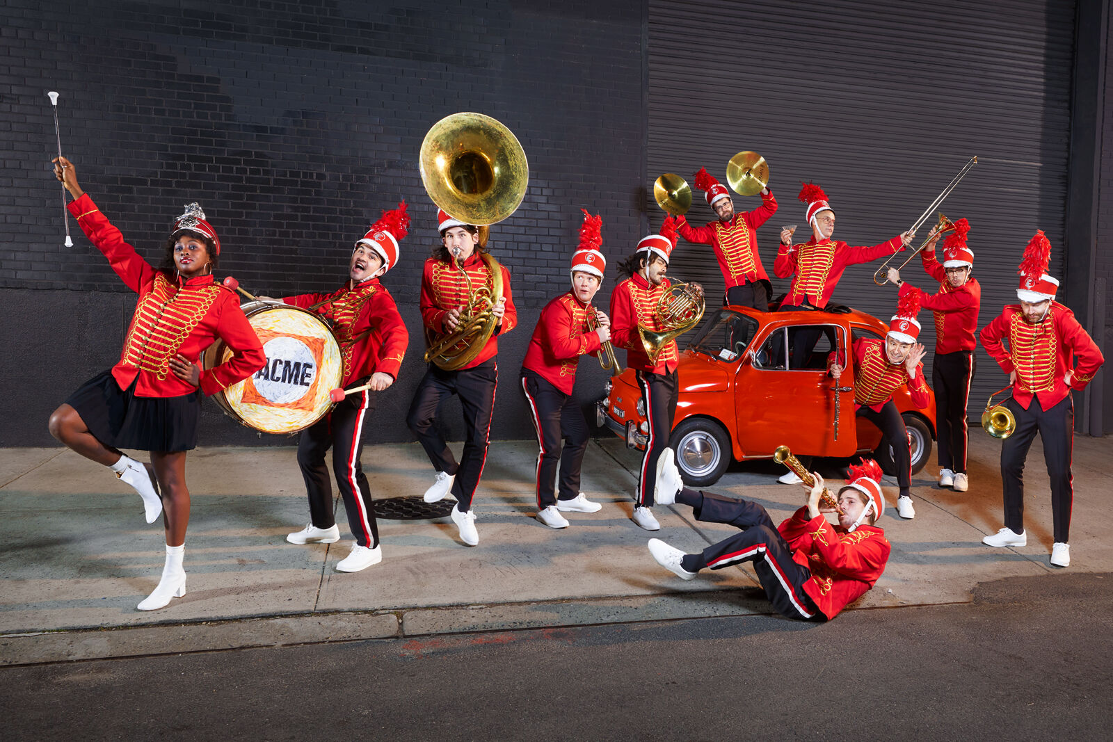 Acme marching band — full crew on the street with red uniforms, brass instruments, and a red truck