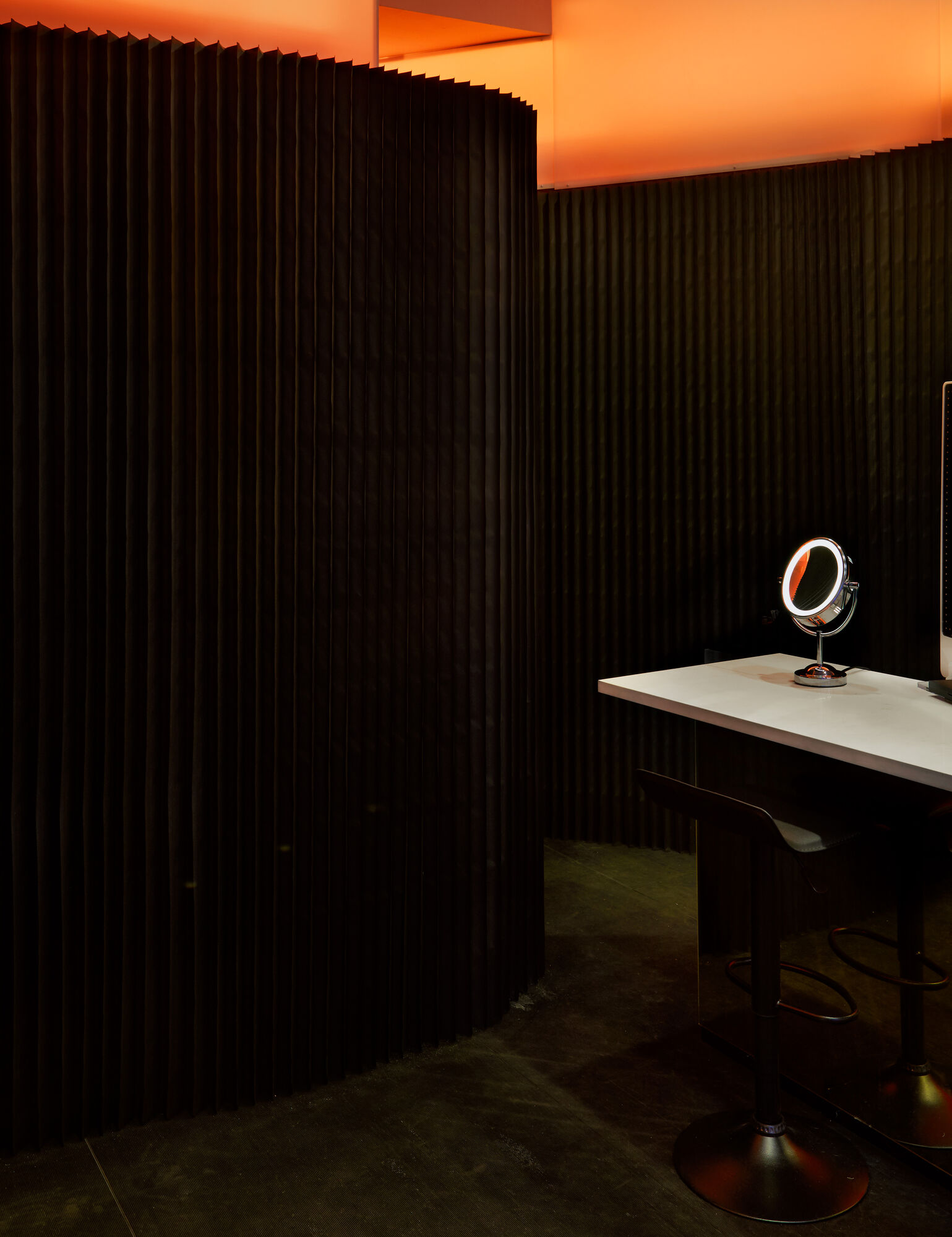 Interior — ribbed walls curve around a vanity station, warm amber glow above
